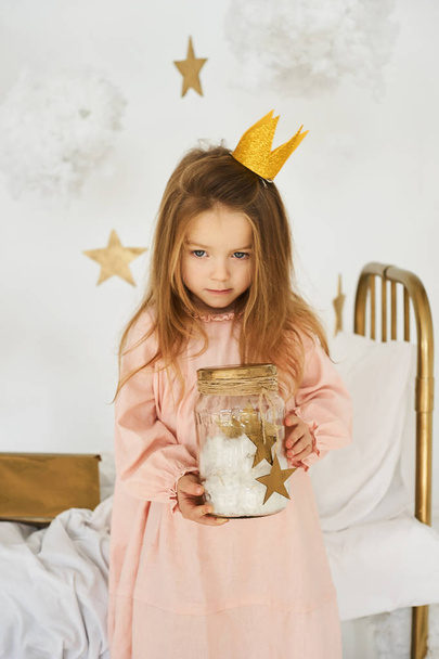 Little princess with a magic wand on  bed in a cloud on a white background - Φωτογραφία, εικόνα
