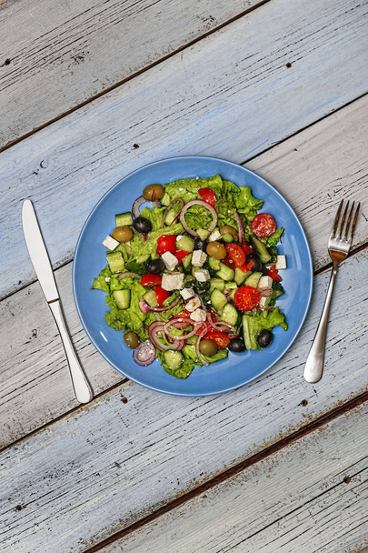 Salade grecque en assiette bleue sur fond bleu bois. Vue de dessus. Espace de copie
 - Photo, image