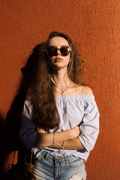 Πορτρέτο του όμορφη έφηβος κορίτσι σε γυαλιά ηλίου θέτοντας κοντά σε κεραμιδί χρώμα τοίχου - Φωτογραφία, εικόνα
