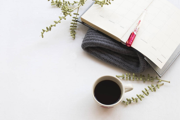 notebook planner  for business work with hot coffee and knitting wool scarf in winter season at office desk on background white  - Foto, Imagen