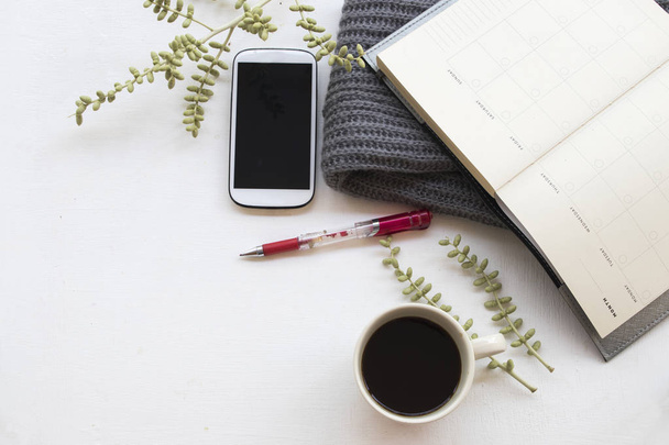 Notizbuch-Planer, Handy für geschäftliche Arbeit mit heißem Kaffee und Strickschal im Winter am Schreibtisch auf weißem Hintergrund  - Foto, Bild