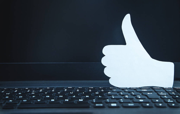 Paper thumbs up sign on laptop keyboard. Social network concept - Photo, Image