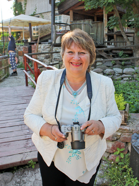 Porträt einer lächelnden Frau mittleren Alters mit Fotokamera - Foto, Bild