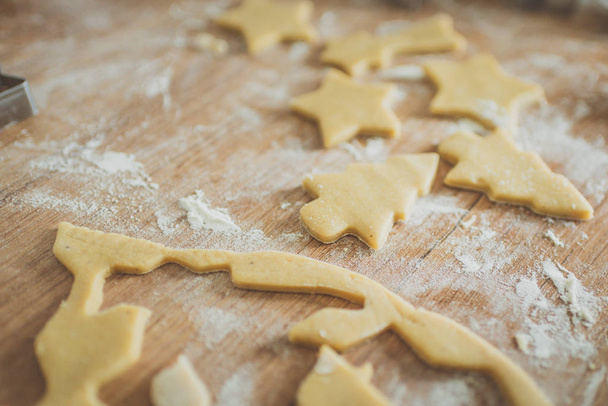 Christmas cookies preparation. Cookies cutter, dough for cookies and rolling pin on the kitchen table. Homemade treats. Selective focus. - Foto, Imagem