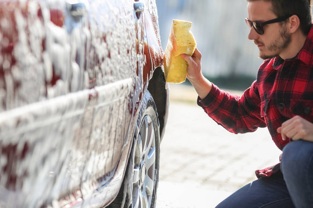 Man worker washing car's alloy wheels on a car wash - Foto, afbeelding