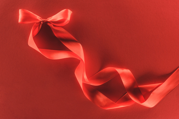 top view of red festive ribbon bow isolated on red, st valentine day concept - Φωτογραφία, εικόνα