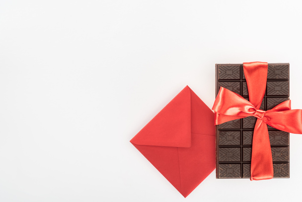 view from above of envelope and delicious chocolate wrapped by festive ribbon isolated on white, st valentine day concept - Photo, Image