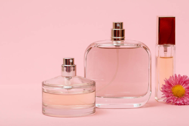 Flaschen mit Frauenparfüm und Blütenknospen vor rosa Hintergrund. Frauenprodukte. - Foto, Bild