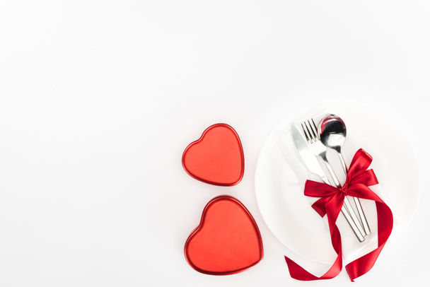 Nézd meg felülről lemez evőeszközök csomagolva ünnepi szalag, szív alakú jelen doboz elszigetelt fehér, Szent Valentin nap koncepció közelében - Fotó, kép