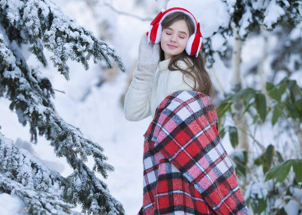 若い女の子がサンタ クロースのヘッドフォンでマンダリンのバスケットと冬の森散歩します。. - 写真・画像