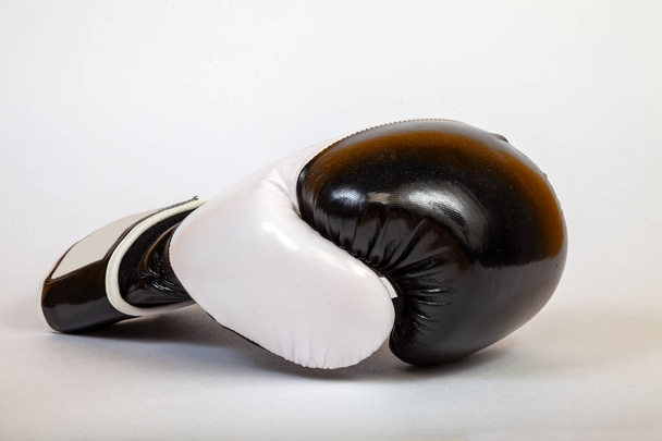 Close-up on a black side turned boxing glove for a blow on a white isolated background. A tool for punishment. - Fotoğraf, Görsel
