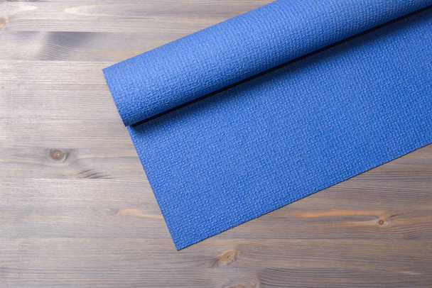 Blue yoga mat on wooden background - Fotoğraf, Görsel