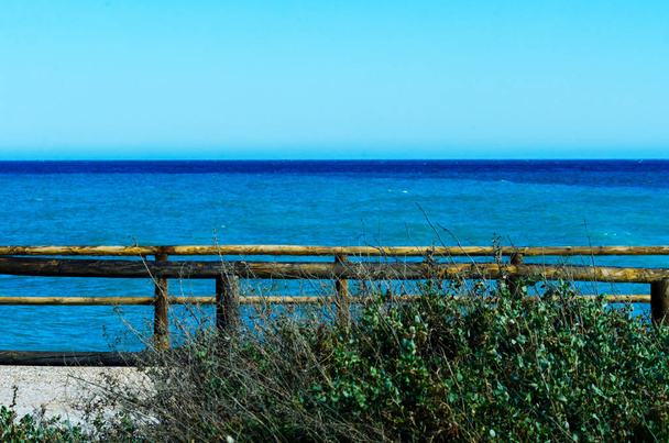 висока скеля над морем з дерев'яним бар'єром, літній морський фон, багато бризок хвиль і камінь, сонячний день
 - Фото, зображення