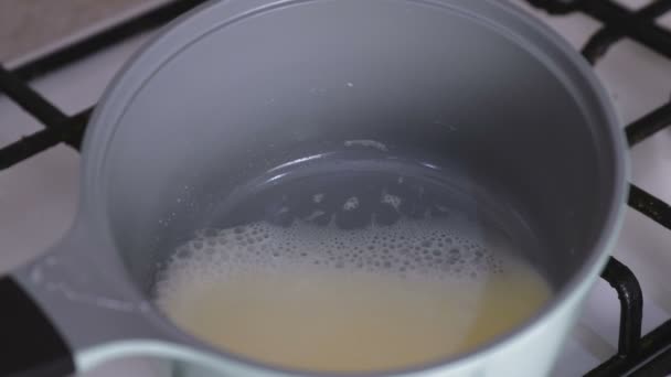 Boiling cream in a saucepan on a gas stove. - Felvétel, videó