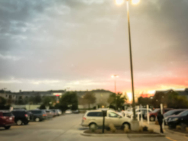 Blurred motion busy parking lots of wholesale store near row of hotels under dramatic sunset cloud - Photo, Image