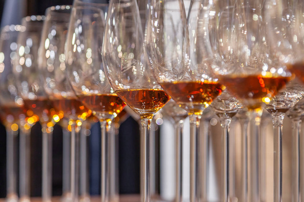 Closeup wijnglazen met cognac staan in de rij op houten planken. Zijaanzicht. Concept van de geesten van de degustatie: whiskey, Cognac, porto, bitter, sherry barmannen sommelier concurrentie en tentoonstelling - Foto, afbeelding