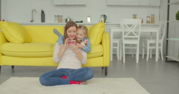 Joyful mum and daughter watching cartoons on phone - Πλάνα, βίντεο
