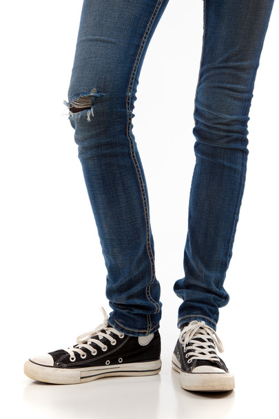 Legs with jeans and retro black sneakers on a white background - Photo, image