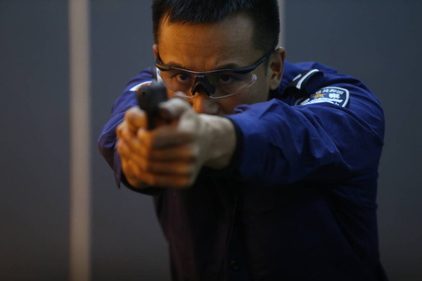 Fang Gang from the Anti-Terror and SWAT team of Beijing Public Security Bureau, who won 6 gold medals at the 2nd World Police Service Pistol Shooting Championship, takes part in a shooting training in Beijing, China, 4 December 2018 - Valokuva, kuva