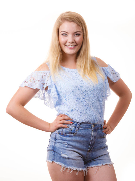 Pretty joyful teen presenting fashion. Young woman wearing stylish blue top and short jeans shorts. - Фото, зображення