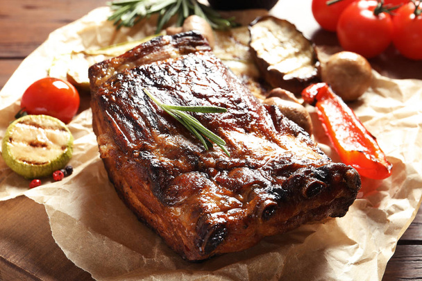 Delicious ribs served with vegetables for barbecue party on wooden table - Photo, Image