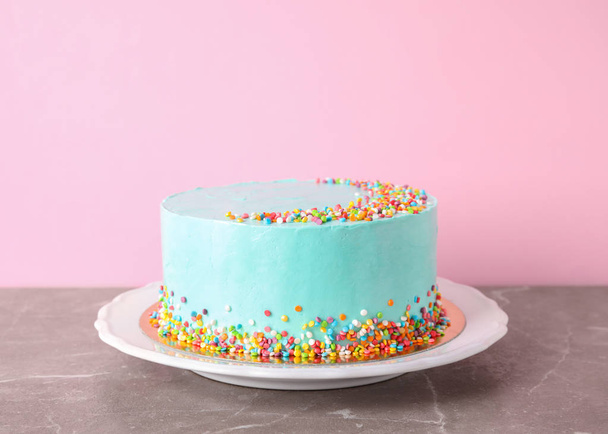Plate with fresh delicious birthday cake on table against color background - Foto, Bild