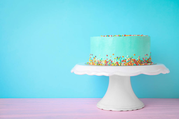 Fresh delicious birthday cake on stand against color background. Space for text - Foto, Bild