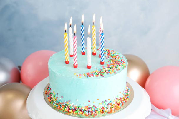 Fresh delicious birthday cake with candles near balloons on color background - Fotografie, Obrázek