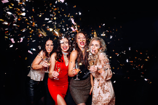 Young attractive women celebrating a party, drinking champagne and dancing. Sparkling confetti, having fun - Photo, Image