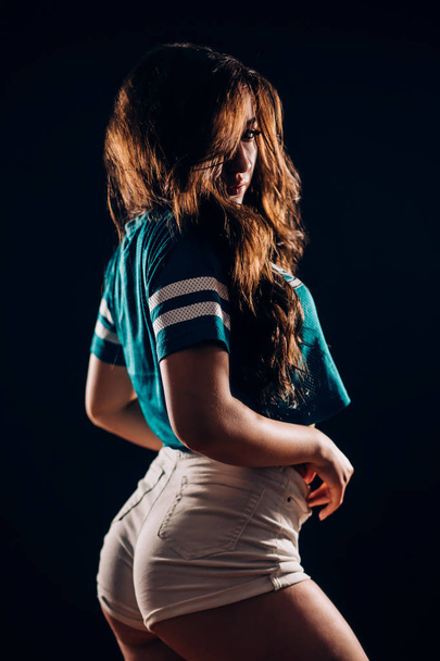 Portrait of beautiful sports fitness or dancer brunette woman in the dark on black background. Sexy girl with long hair smiling and looking at camera - Foto, Bild