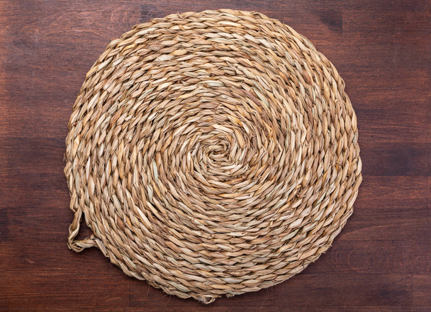 Empty trivet Of natural fibers. On dark wood background. Concept to include your food and your text. - Photo, Image