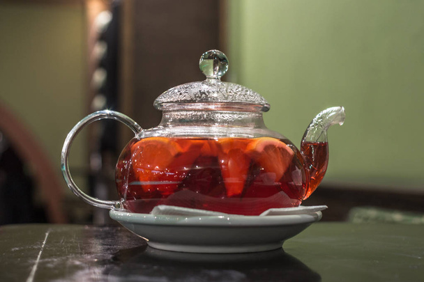 Glass teapot. Fruit and citrus tea. Hot morning drink. A warming drink with pieces of fruit. Glass teapot for tea. Beautiful tea service in the restaurant. - Photo, Image