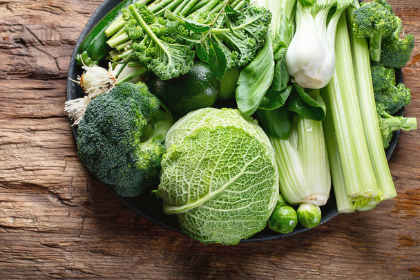 top view of Fresh green vegetables on wooden table in kitchen - Foto, Bild