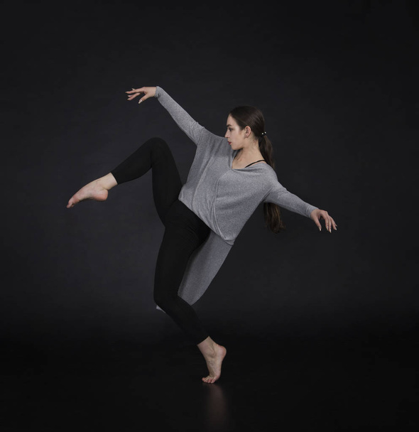 Girl in a dress dances and modern choreography. Studio shot on dark background - Photo, Image