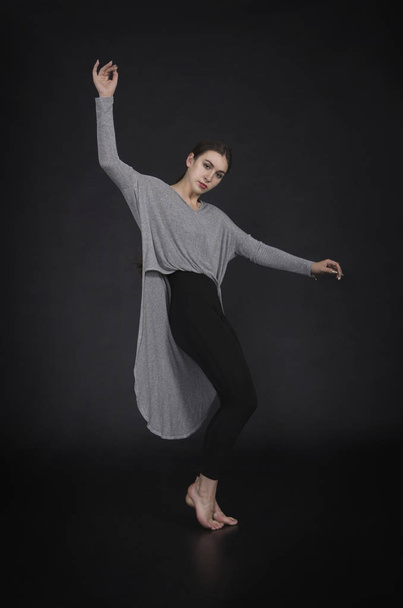 Girl in a dress dances and modern choreography. Studio shot on dark background - Zdjęcie, obraz