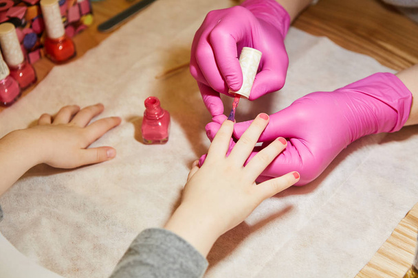 Little girl is getting manicure in beauty salon, close-up. - Foto, imagen