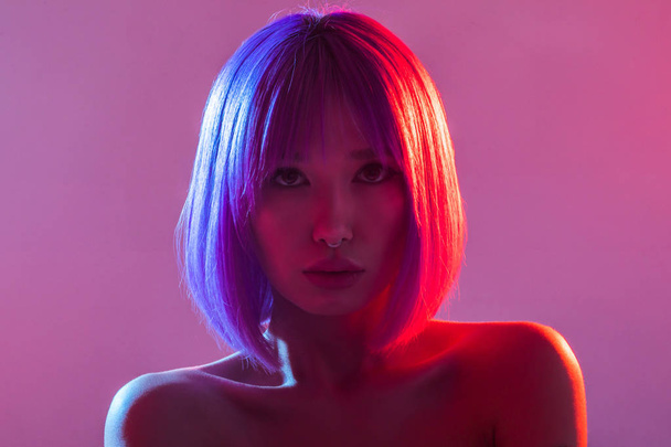 Woman in colorful bright lights posing in studio. - Foto, Imagem