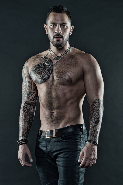 Masculinity and brutality. Tattoo culture concept. Tattoo brutal attribute. Man brutal unshaven hispanic appearance tattooed arms. Bearded man show tattooed torso. Brutal strict macho with tattoos - Photo, image