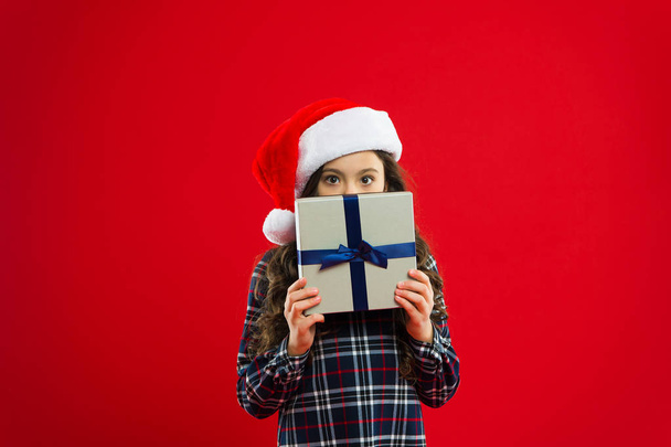 Happy winter holidays. Small girl. New year party. Santa claus kid. Little girl child in santa red hat. Present for Xmas. Childhood. Christmas shopping. dont be shy - 写真・画像