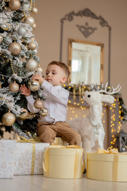 маленький хлопчик прикрашає ялинку на Різдво
. - Фото, зображення