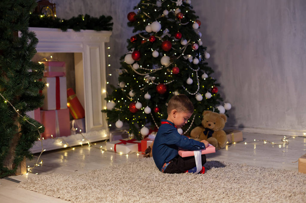 mały chłopiec otwiera Boże Narodzenie nowy rok prezenty choinki Garland - Zdjęcie, obraz