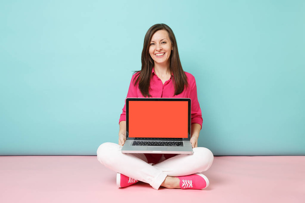 Full length portrait of young woman in rose shirt blouse white pants sitting on floor using laptop pc isolated on pink blue pastel wall background studio. Fashion lifestyle concept Mock up copy space - Photo, Image