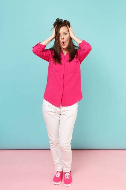 Full length portrait of smiling young pretty woman in rose shirt blouse, white pants posing isolated on bright pink blue pastel wall background studio. Fashion lifestyle concept. Mock up copy space - Foto, imagen
