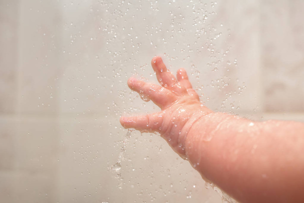 Hand Of Newborn Caucasian Baby Under Shower Close Up With Lots Of Splashes. - Fotografie, Obrázek