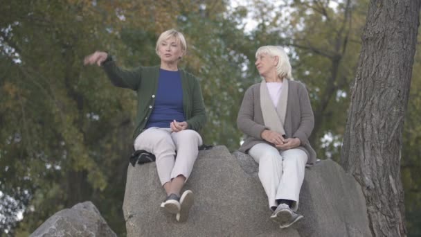 Madre mayor e hija de mediana edad sentadas en piedras y hablando de la vida
 - Metraje, vídeo