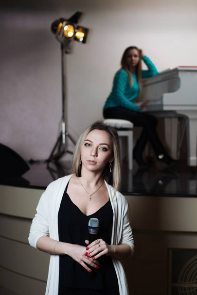 One girl sings in a restaurant, and behind her colleague plays the piano. - Foto, Imagem