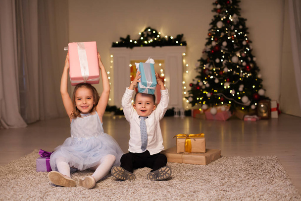 ein Junge mit einem Mädchen öffnet Weihnachten Geschenke neue Jahr Urlaub Girlanden Lichter - Foto, Bild