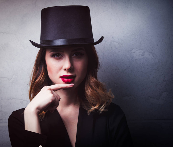 Stile e mistica rossa ragazza in cappello a cilindro su sfondo grigio
 - Foto, immagini