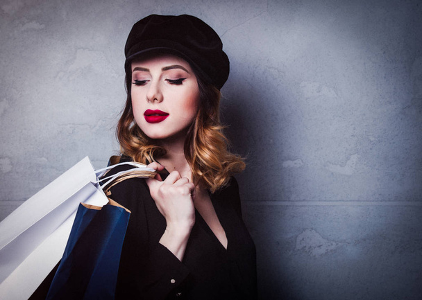 Style redhead girl in hat with shopping bags on grey background - Фото, зображення