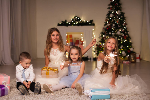 Niños abren regalos de Navidad año nuevo luces de vacaciones chispas
 - Foto, imagen